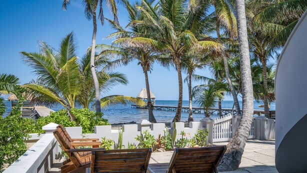 A beachside lounge with wooden chairs and a view of the ocean. - Sandcastle Sunset view Ocean front apartment with pool (San Pedro)