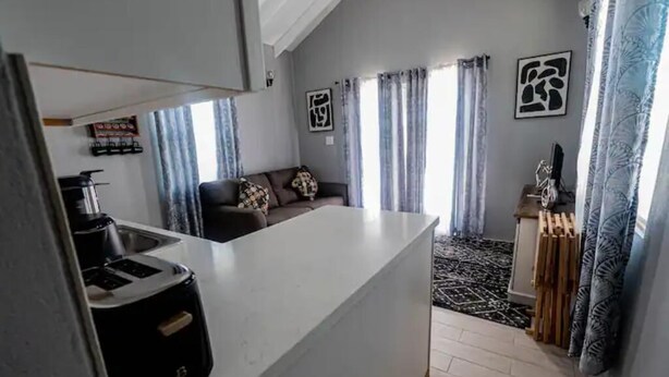 A compact living space with a kitchenette, a sofa, and a patterned rug. - De ja Blue (Saint George)