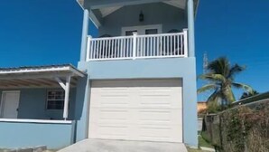 A two-story house with a white garage door, a balcony, and a clear blue sky. - De ja Blue (Saint George)