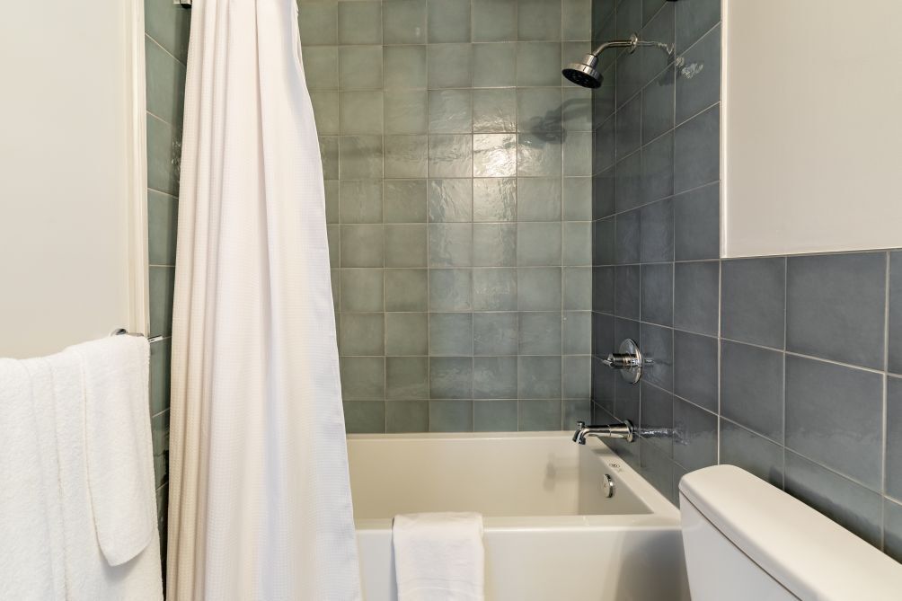 Een badkamer met een bad, douche en toilet.