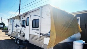 Een grote camper met een overdekte slaapruimte, een keuken en een badkamer.