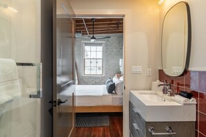 A modern bedroom with a bed, a large mirror, and a bathroom with a sink and toilet.