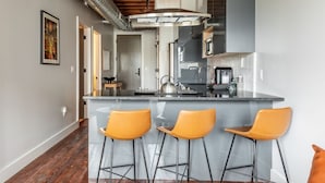 Una cocina moderna con una isla central, taburetes de bar y electrodomésticos de acero inoxidable.