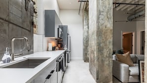 A modern kitchen with a large island, stainless steel appliances, and a view into the living area. - Historic Charm Meets Luxury in This Central Warehouse Retreat (New Orleans)