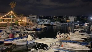 A marina at night with boats docked, a building with lights, and a palm tree. - Vacation home (Historical Center) CATANIA (Catania)