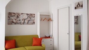 A modern living room with a green sofa, a white wardrobe, and a mirror. - Vacation home (Historical Center) CATANIA (Catania)