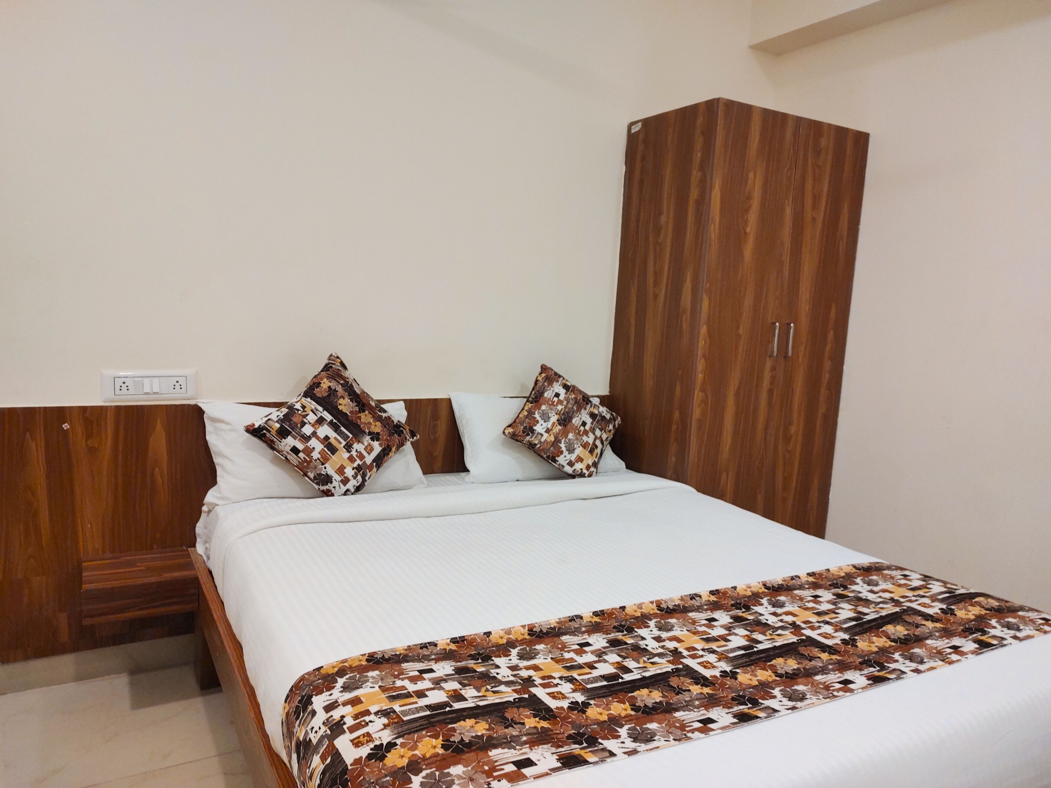 A bedroom with a wooden headboard, a bed with patterned pillows, and a wardrobe.