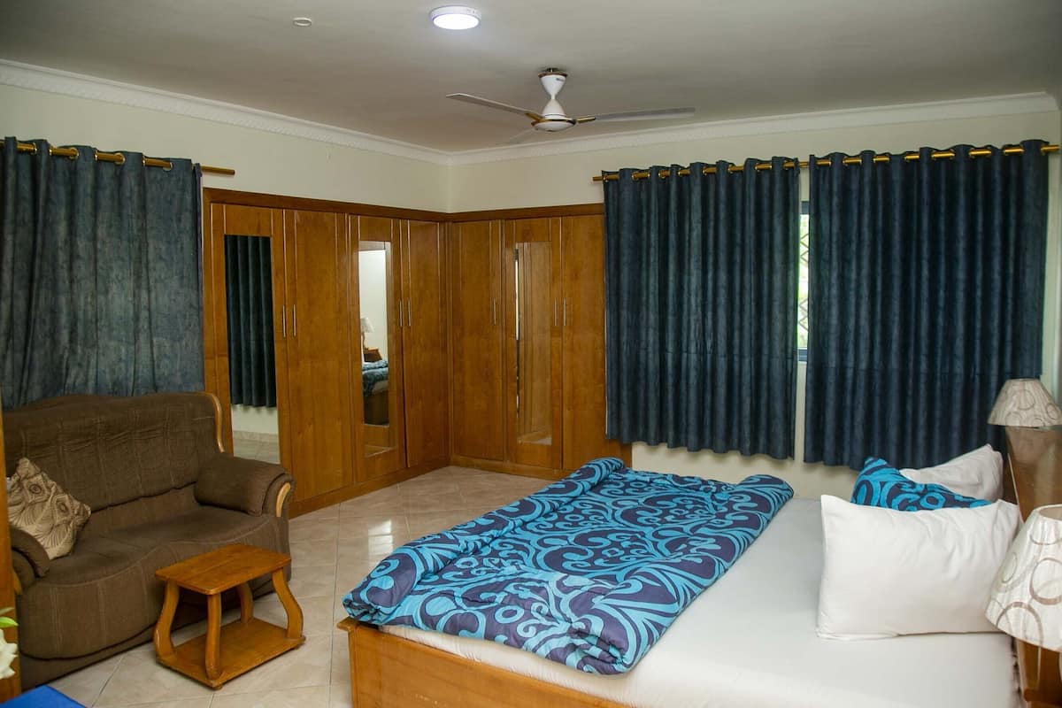 A bedroom with a bed, a sofa, a small table, and a wardrobe.