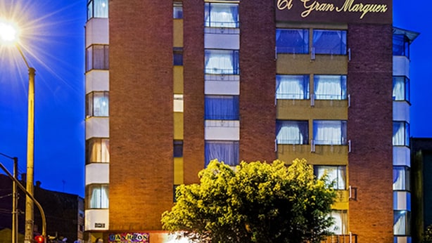 A hotel named El Gran Marquez with a brick facade, multiple windows, and a tree in front. - Hotel Gran Marquez (Bogotá)