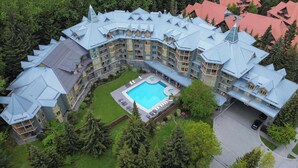 Un grand hôtel à plusieurs étages, doté d’une piscine centrale entourée de chaises longues.