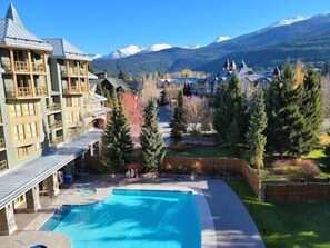 Een hotel met een zwembad, omgeven door bergen en bomen.