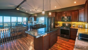 Una cocina amplia con una isla grande, armarios de madera y vistas al exterior.