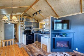 Une cuisine moderne dotée d’un four encastré, d’un four à micro-ondes et d’un évier, un coin repas avec une table en bois et une cheminée.