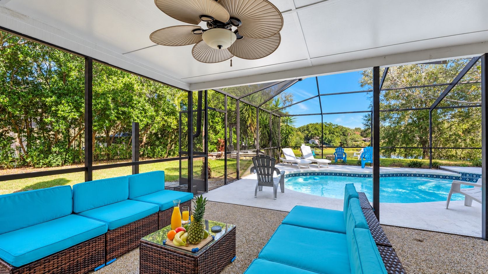 Eine Terrasss mit Pool, blauen Sitzmöbeln und Deckenventilator.