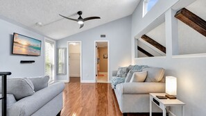Un vaste espace de vie doté d’un ventilateur de plafond, d’un téléviseur à écran plat et d’un canapé.