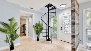 Un intérieur moderne agrémenté d’un escalier en colimaçon, de plantes en pot et d’une porte décorative.