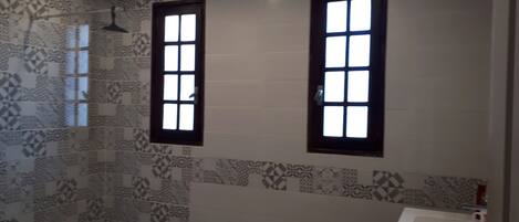 A bathroom with patterned tiles, two windows, and a sink.