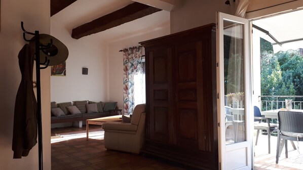 A cozy living area with a sofa, a chair, and a wooden door leading to an outdoor patio.