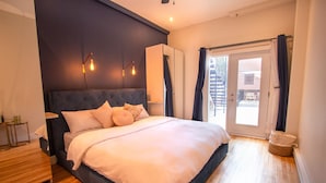 Un dormitorio con una cama grande, un armario, una mesita de noche y vistas al exterior.