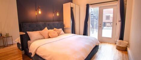 Un dormitorio con una cama grande, un armario, una mesita de noche y vistas al exterior.