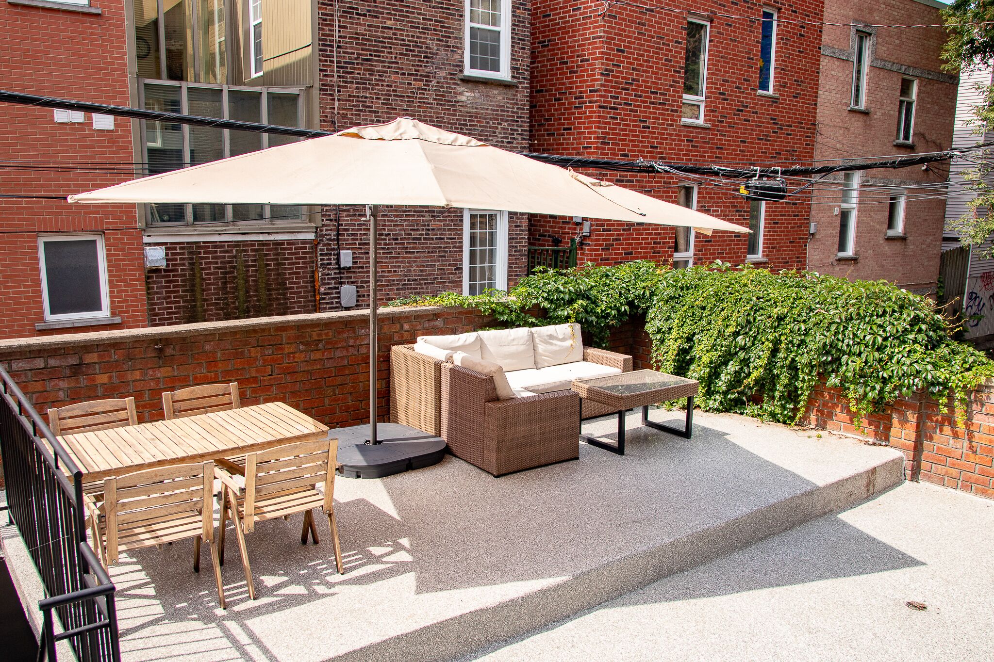 A patio with a table and chairs, a sofa, and a large umbrella.