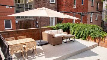 A patio with a table and chairs, a sofa, and a large umbrella.