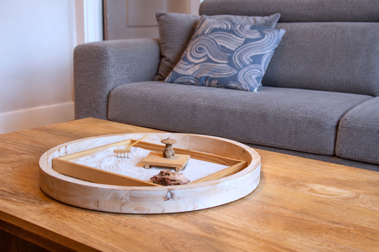 A round wooden tray with a miniature model on a wooden table.