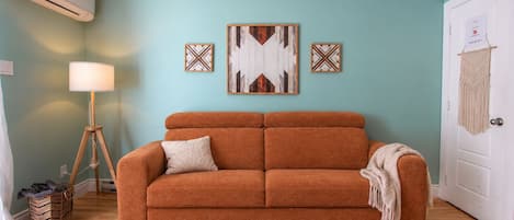 A living room with a sofa, a lamp, and wall art.