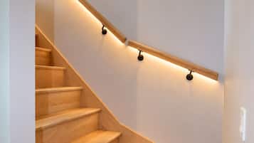 Una scala in legno dalla forma curva con illuminazione a parete.