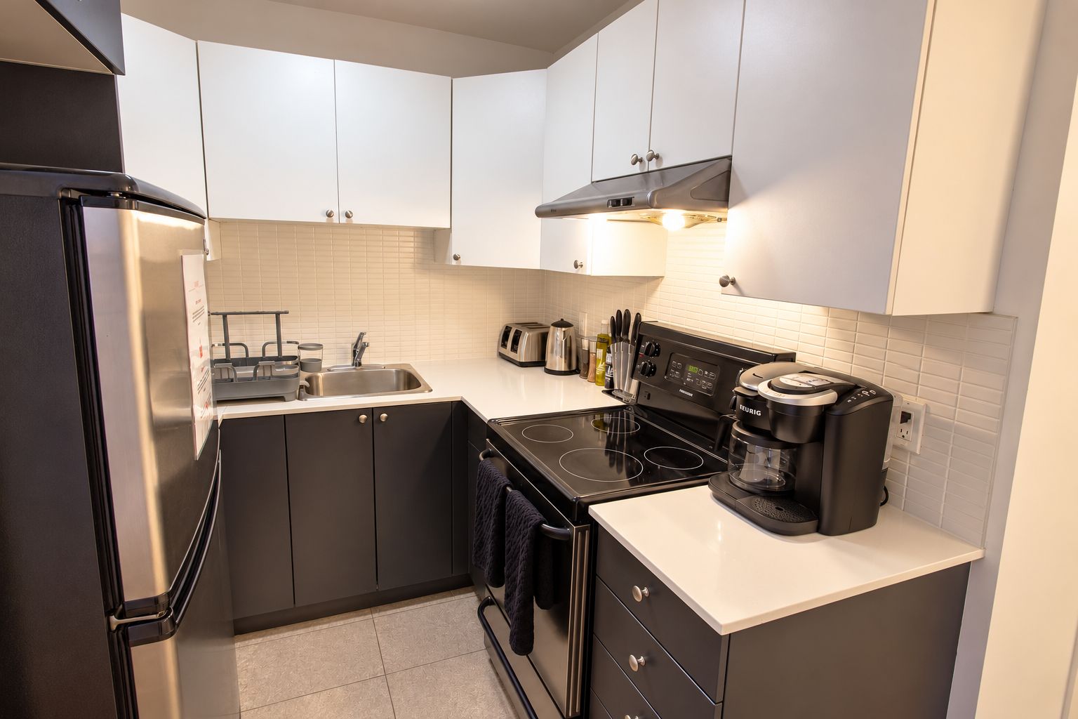 Una cucina compatta con frigorifero, fornello e macchina da caffè.