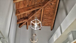 A ceiling with exposed wooden beams and a geometric light fixture.