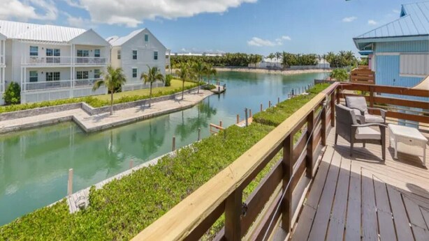A waterfront property with a wooden deck, a pool, and a view of a river.
