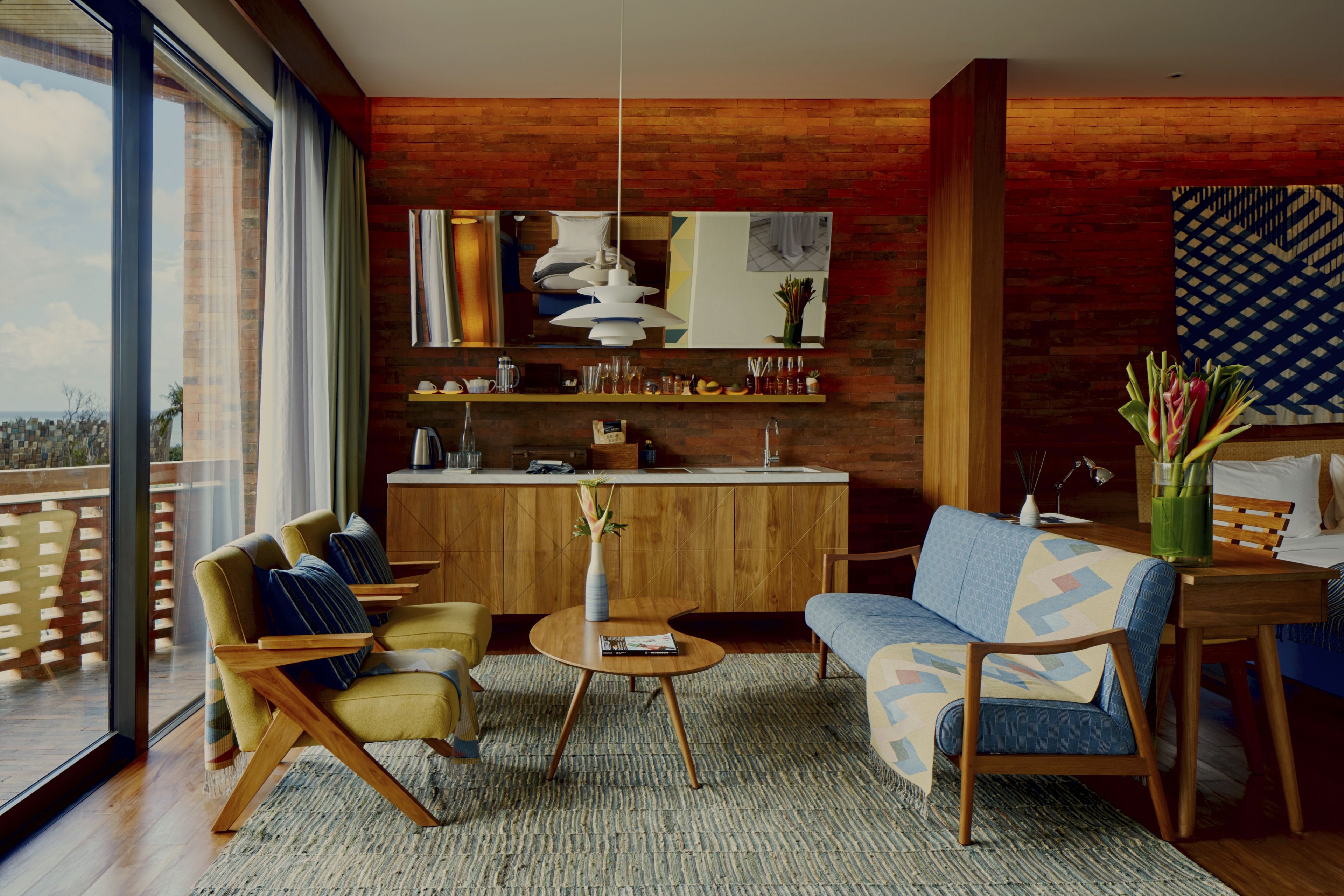 A modern living room with a sofa, armchairs, a coffee table, and a dining area with a kitchen in the background.
