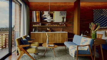 Una sala de estar moderna con un sofá, sillones, una mesa de centro y un comedor con una cocina al fondo.