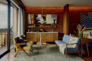 A modern living room with a sofa, armchairs, a coffee table, and a dining area with a kitchen in the background.