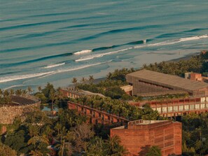 A coastal hotel with a view of the ocean, featuring a modern building with a flat roof and a swimming pool. - Desa Potato Head Bali (Keroboken Kelod)