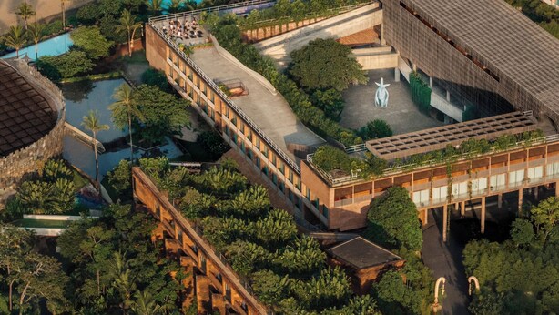 Vue aérienne d’un complexe hôtelier doté d’une piscine, d’une plage et d’une végétation luxuriante.
