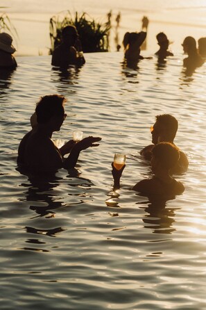 Des personnes dans une piscine, tenant chacune un verre à la main.