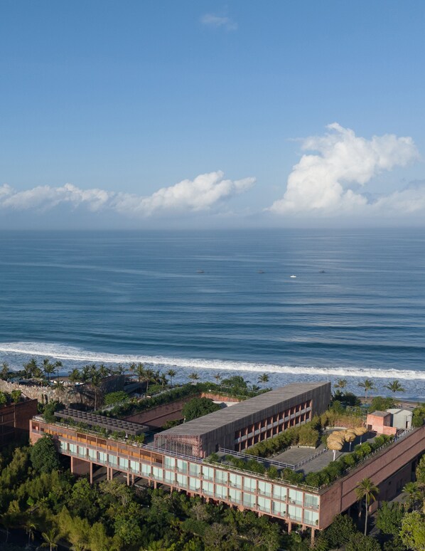 A coastal hotel with a view of the ocean, featuring a modern building with a flat roof and a long structure with a glass facade. - Desa Potato Head Bali (Keroboken Kelod)