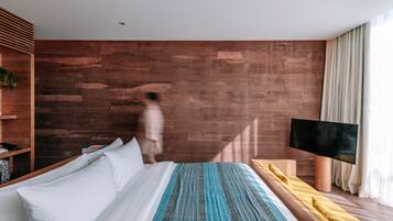 Una habitación de hotel moderna con un revestimiento de madera, una cama con ropa de cama blanca y estampada, un televisor y una mesita de noche.