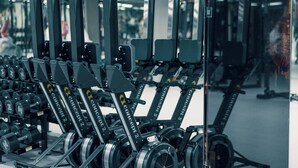 Une salle de sport équipée de divers appareils de musculation, notamment des haltères et des disques de poids, disposés sur des supports.