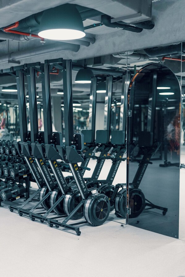 A gym with various weightlifting equipment, including dumbbells and weight plates, arranged on racks. - Desa Potato Head Bali (Keroboken Kelod)