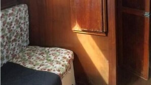 Interior d'una autocaravana compacta, amb un llit, una zona d'seients petita i un armari de fusta.