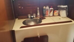 Una cuineta petita amb un rentatge, un mirall i diversos productes de tocador, com ara ampolles i una bossa de mocadors.