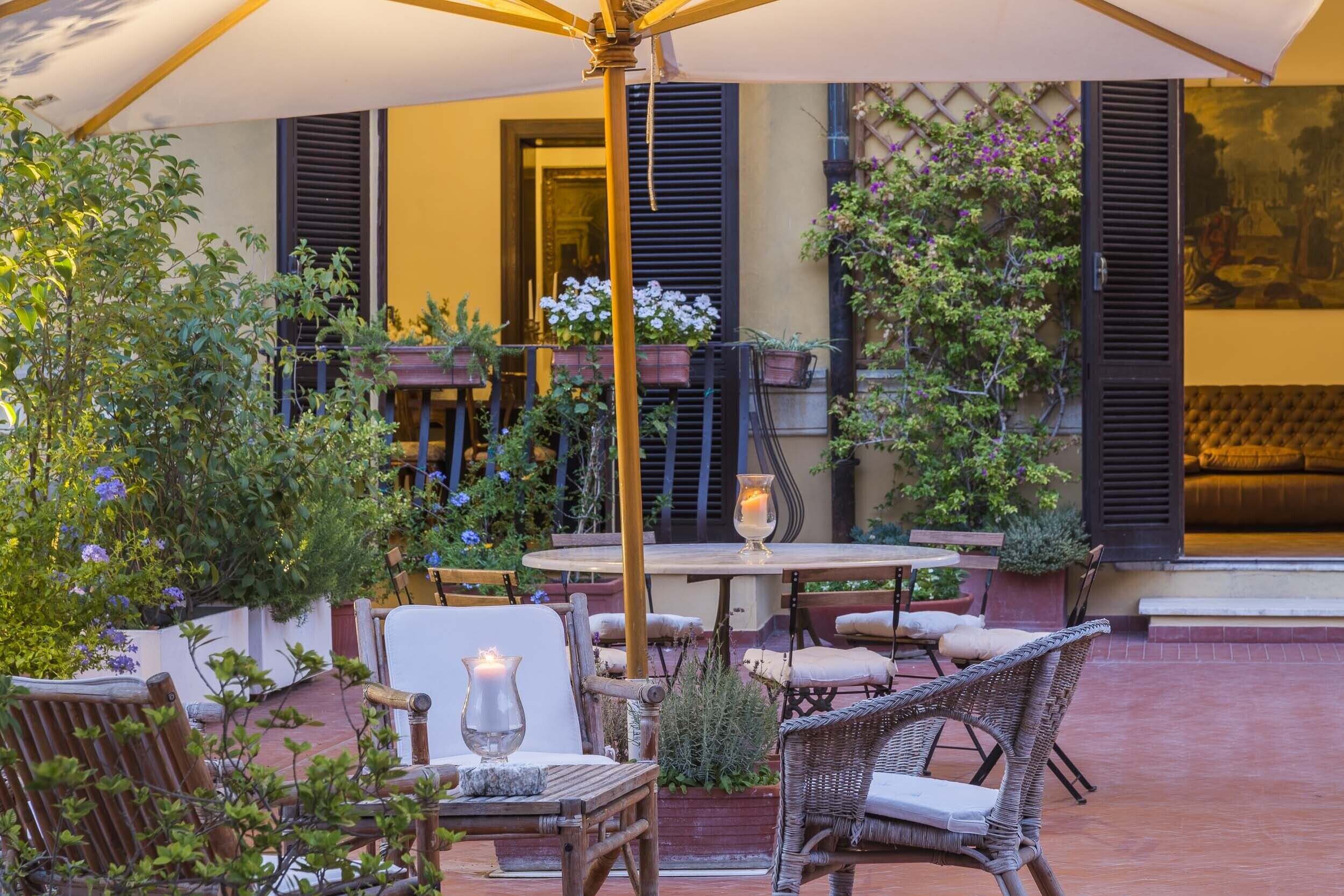 Un patio al aire libre con mobiliario de mimbre, una mesa y plantas en macetas.