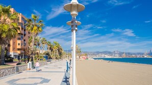 A beachfront promenade with a white lamp post, palm trees, and a clear blue sky. - Cubo's Apartamento Seaview Port & Free Parking / sea views / free wifi (Málaga)