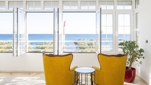 A room with two yellow armchairs and a small round table, large windows with a view of the sea, and a potted plant. - Cubo's Apartamento Seaview Port & Free Parking / sea views / free wifi (Málaga)
