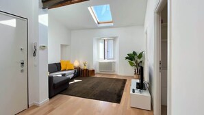 A modern living room with a sofa, a small table with a lamp, a radiator, and a skylight. - Casa Moira - Affitti Brevi Italia (Lecco)