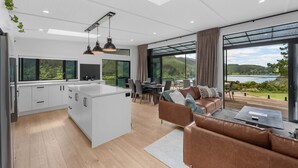 A modern kitchen with white cabinets, a central island, and pendant lighting. - Lakeview Oasis - Lake Whakamaru Retreat (Mangakino)