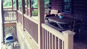 Une véranda couverte avec une balustrade en bois, une table et des chaises.